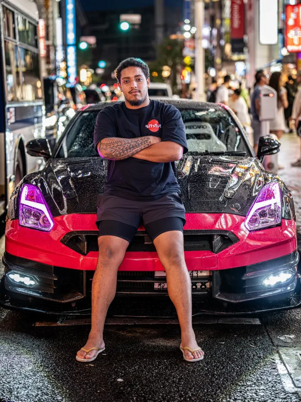 San - Your Driver & Guide sitting on the hood of the pink GT-R in Tokyo at night